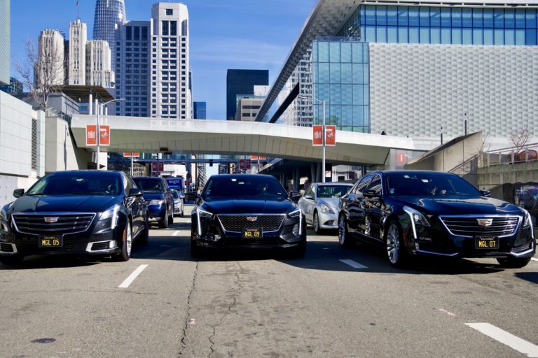 3 Executive black car limos driving down a street in SF