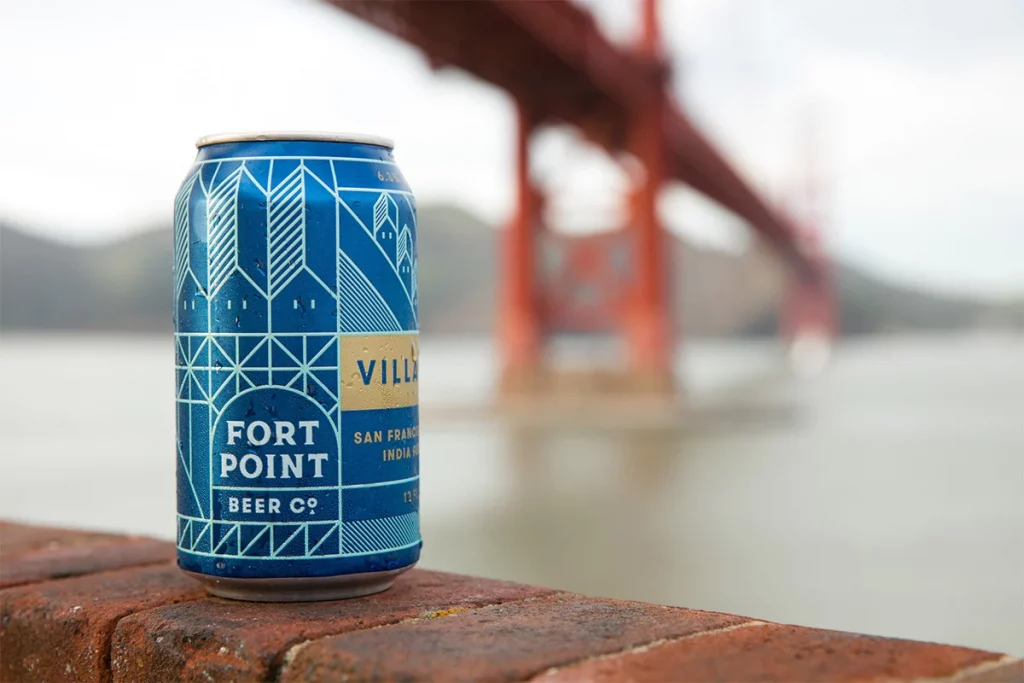 A photo of a beer can with the Fort Point Beer Company logo on it, against the golden gate bridge background.