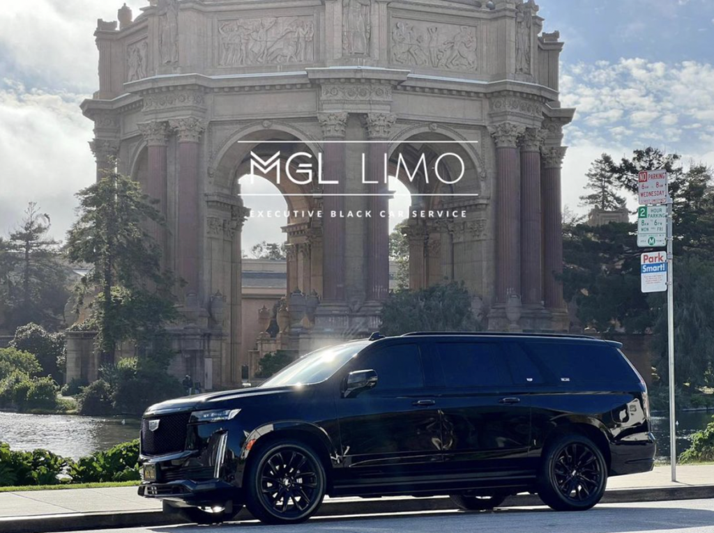 A black cadillac escalade in front of the palae of fine arts in San Francisco on a sunny day.